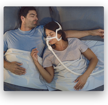 A couple sleeping while one uses their CPAP device